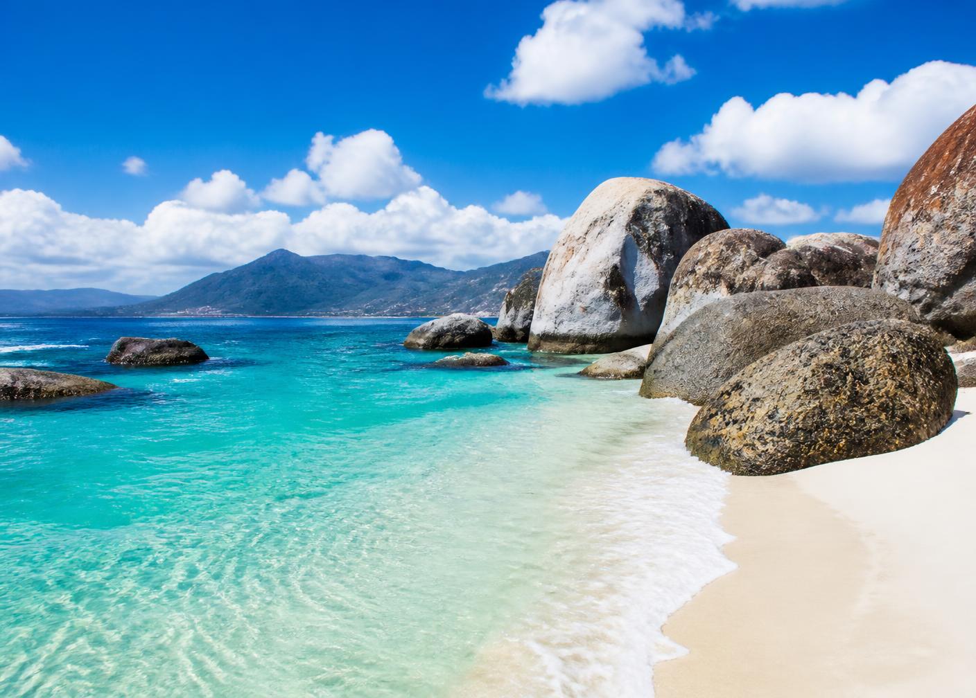 Turquoise water over white sand between granite boulders