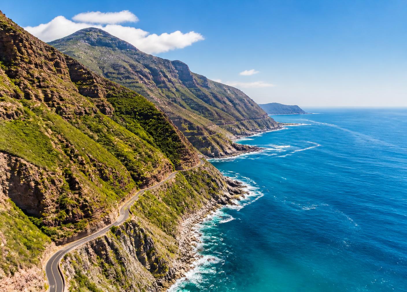 An open coastal road unwinding toward distant mountains at golden hour